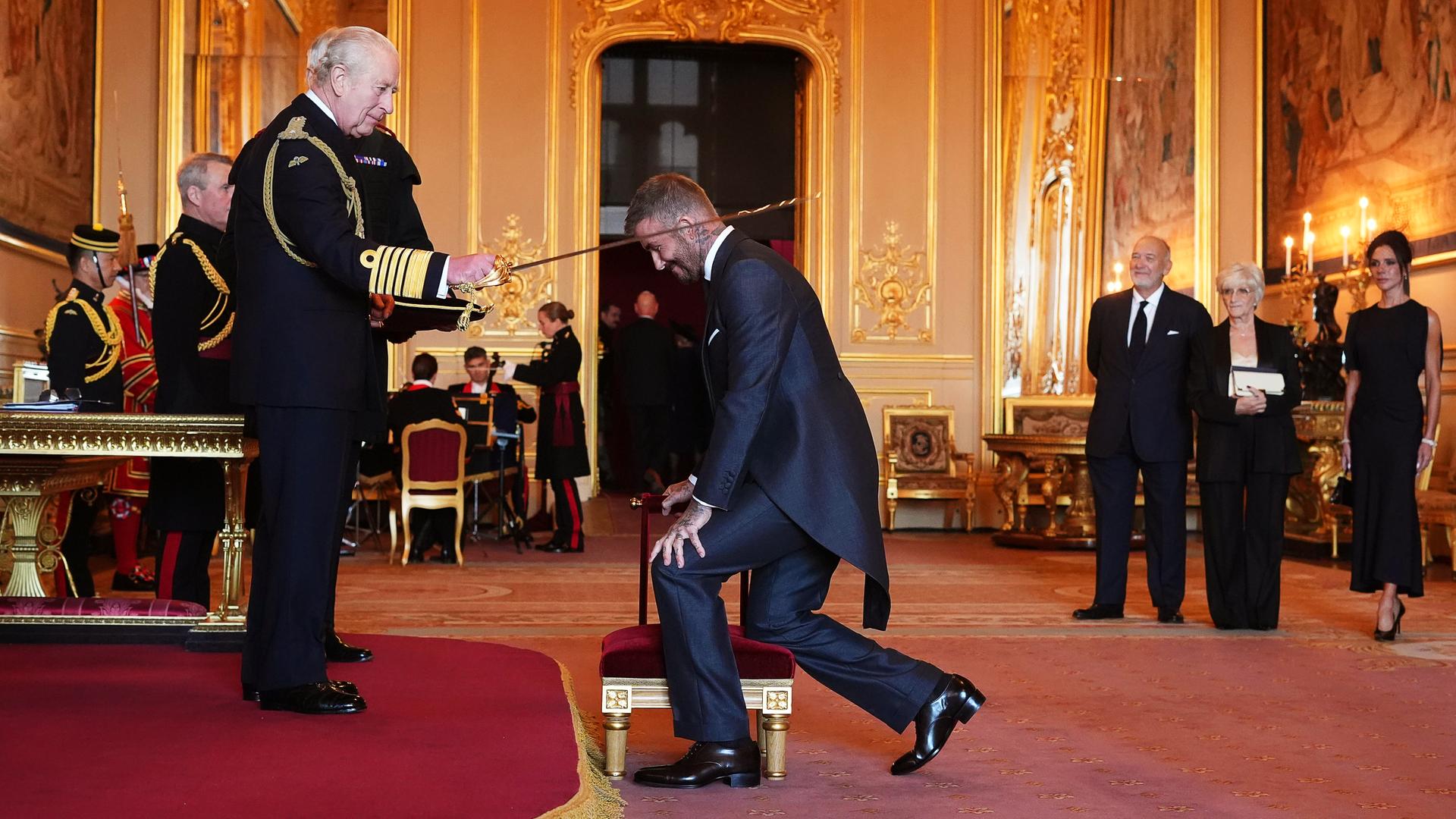 Sir David Beckham (Mitte) wird von König Charles III. (links) während einer Zeremonie auf Schloss Windsor in den Ritterstand erhoben.
