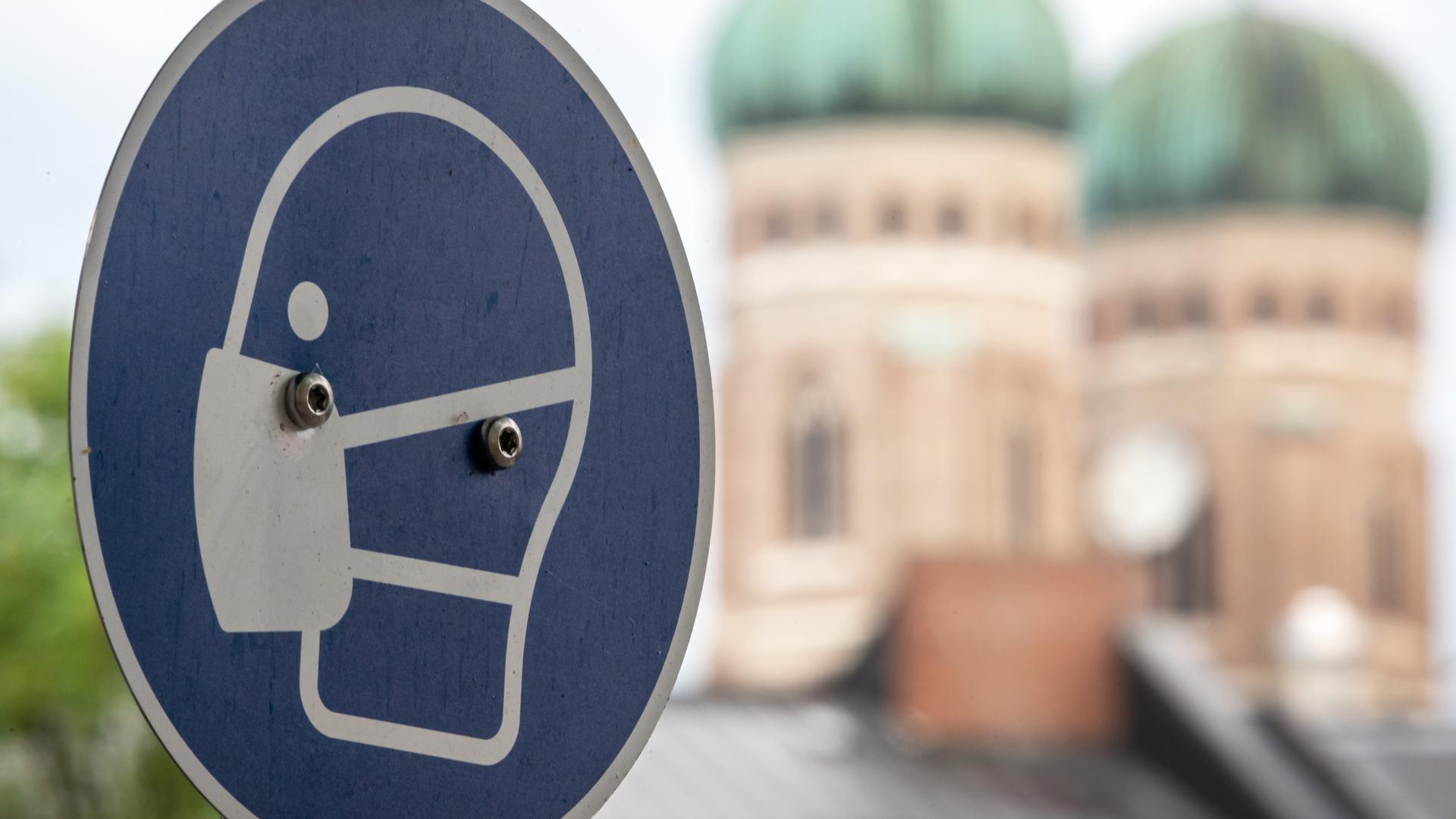 ein schild fordert am viktualienmarkt in der münchner innenstadt zum tragen einer mund und nasen bedeckung auf