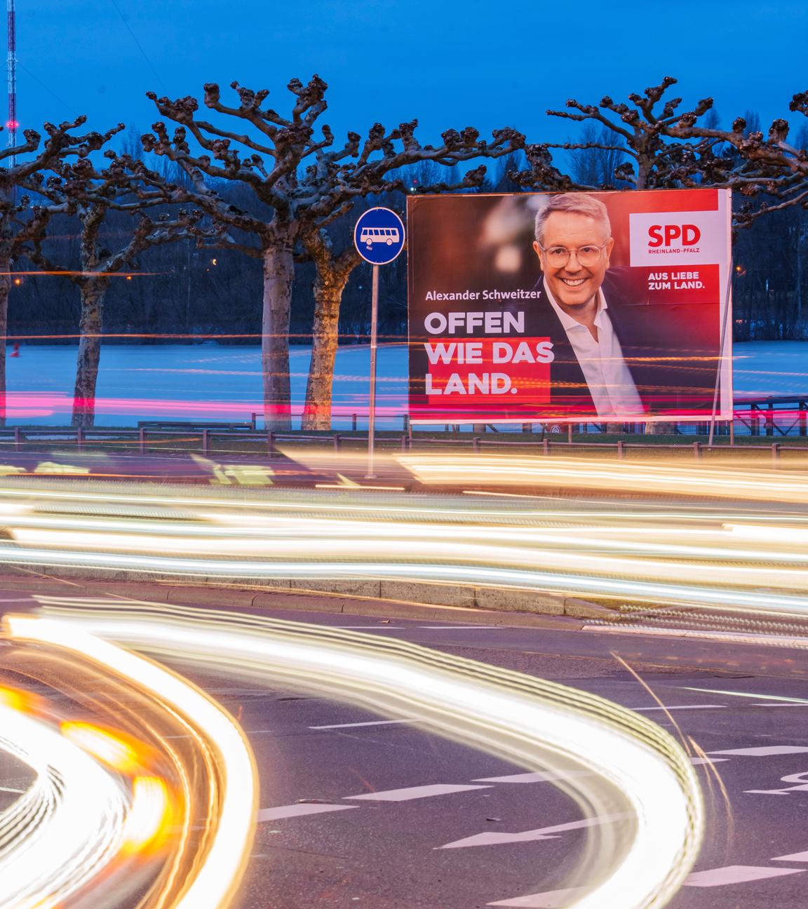  Vorbeifahrende Fahrzeuge erzeugen auf der Rheinallee Lichtstreifen vor den Wahlplakaten von Gordon Schnieder, CDU-Landeschef und Spitzenkandidat seiner Partei zur anstehenden Landtagswahl, mit Isabell Rahms, Landtagskandidatin ihrer Partei für Mainz zur anstehenden Landtagswahl, und Alexander Schweitzer.
