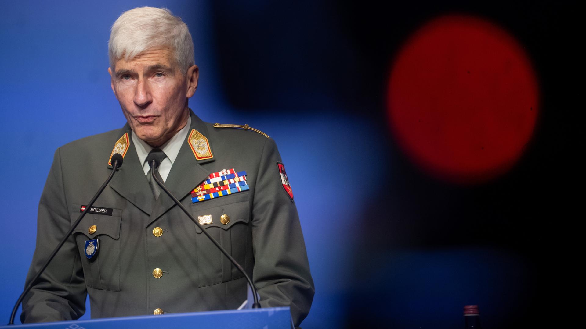 Robert Brieger steht in Uniform an einem Pult mit der Aufschrift HU24EU und hält eine Rede.