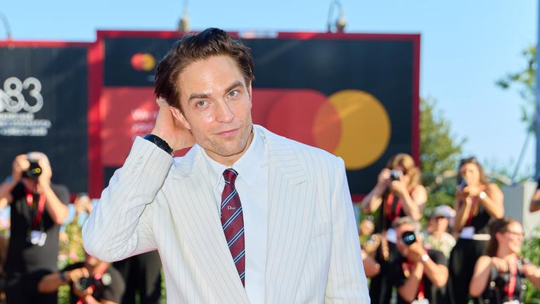 Robert Pattinson posiert vor  Kameras auf einem Event. 
