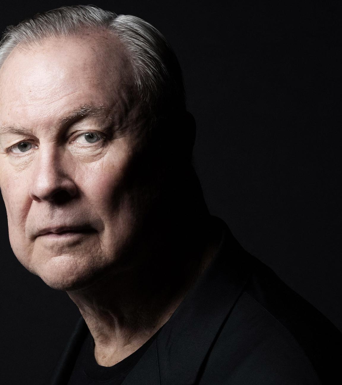 Robert Wilson schwarz gekleidet vor schwarzem Hintergrund