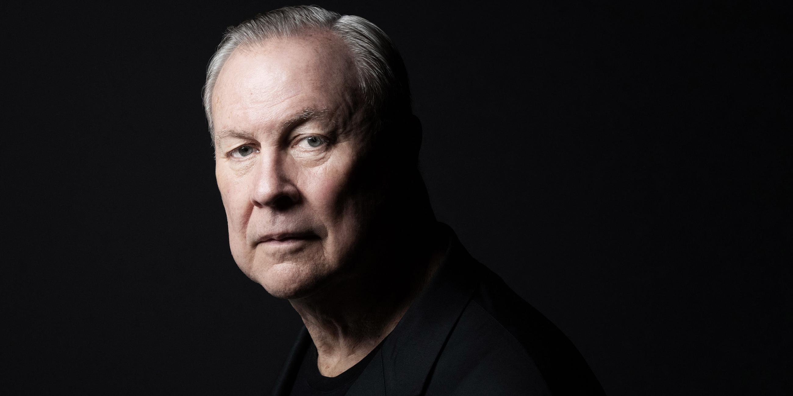 Robert Wilson schwarz gekleidet vor schwarzem Hintergrund