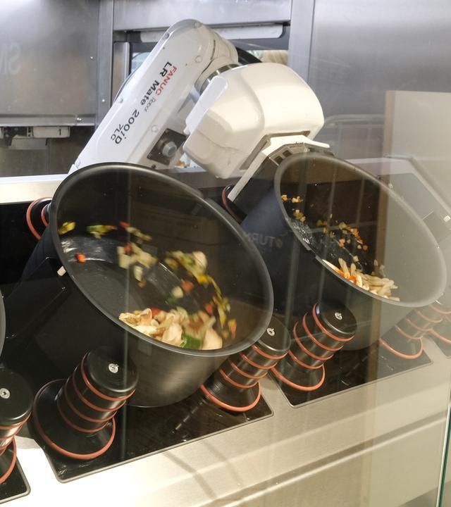 Ein Roboterarm arbeitet im Robyns, einem vollständig automatisierten Restaurant im Leipziger Hauptbahnhof, an einem Kochvorgang.