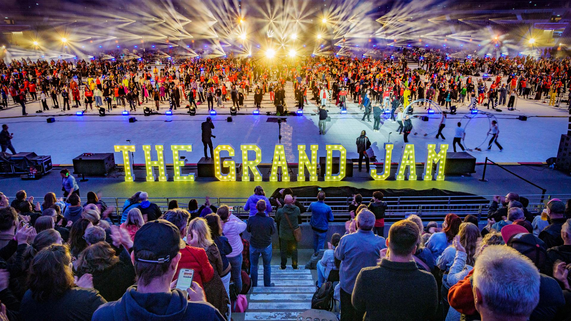 Zuschauer im Frankfurter Waldstadion. "The Grand Jam" steht in Leuchtschrift vor der Bühne.