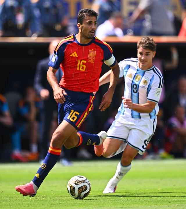 Der ballführende spanische Nationalspieler Rodri wird von seinem argentinischen Gegenspieler Julian Alvarez von hinten bedrängt