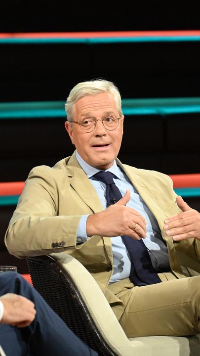 Röttgen gestikuliert in hellem Anzug im TV-Studio von Markus Lanz.
