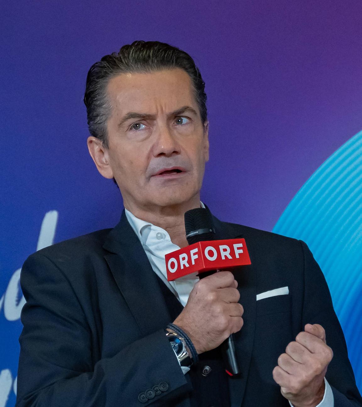 Roland Weißm,ann mit ernstem Blick und einem ORF-Mikrofon in der Hand.