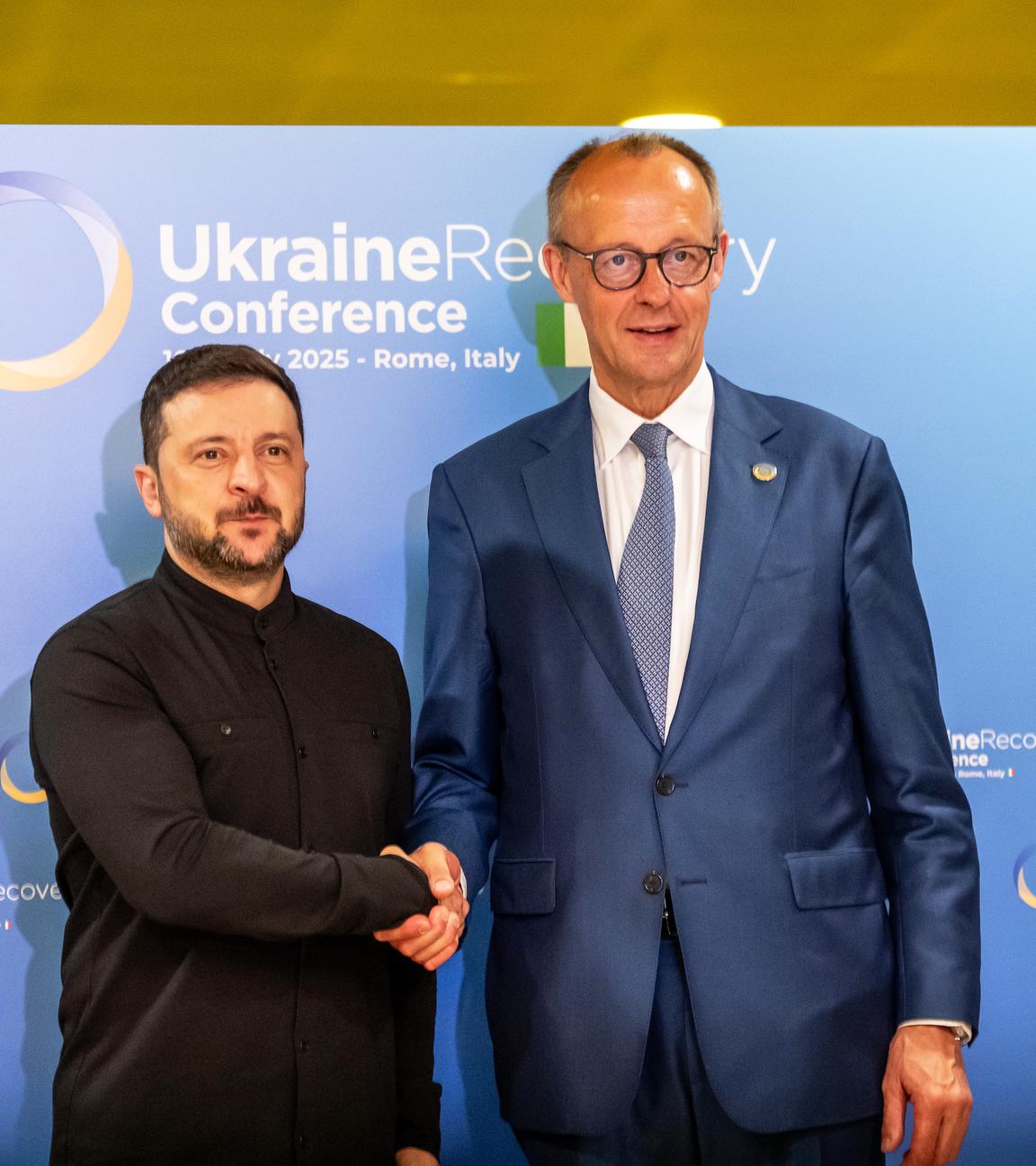 Bundeskanzler Friedrich Merz (CDU, r) und Wolodymyr Selenskyj, Präsident der Ukraine, geben sich vor einem bilateralen Gespräch bei der Wiederaufbaukonferenz für die Ukraine die Hand.