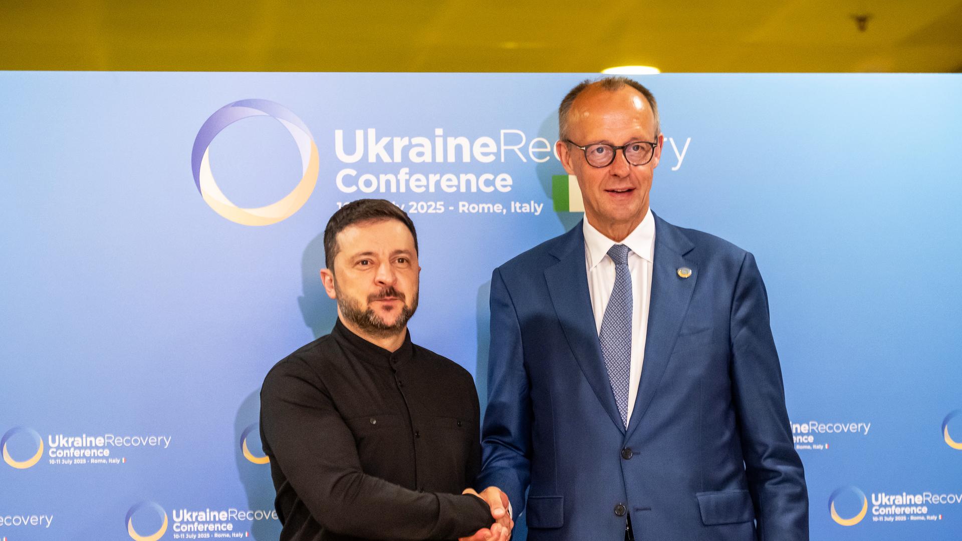 Bundeskanzler Friedrich Merz (CDU, r) und Wolodymyr Selenskyj, Präsident der Ukraine, geben sich vor einem bilateralen Gespräch bei der Wiederaufbaukonferenz für die Ukraine die Hand.