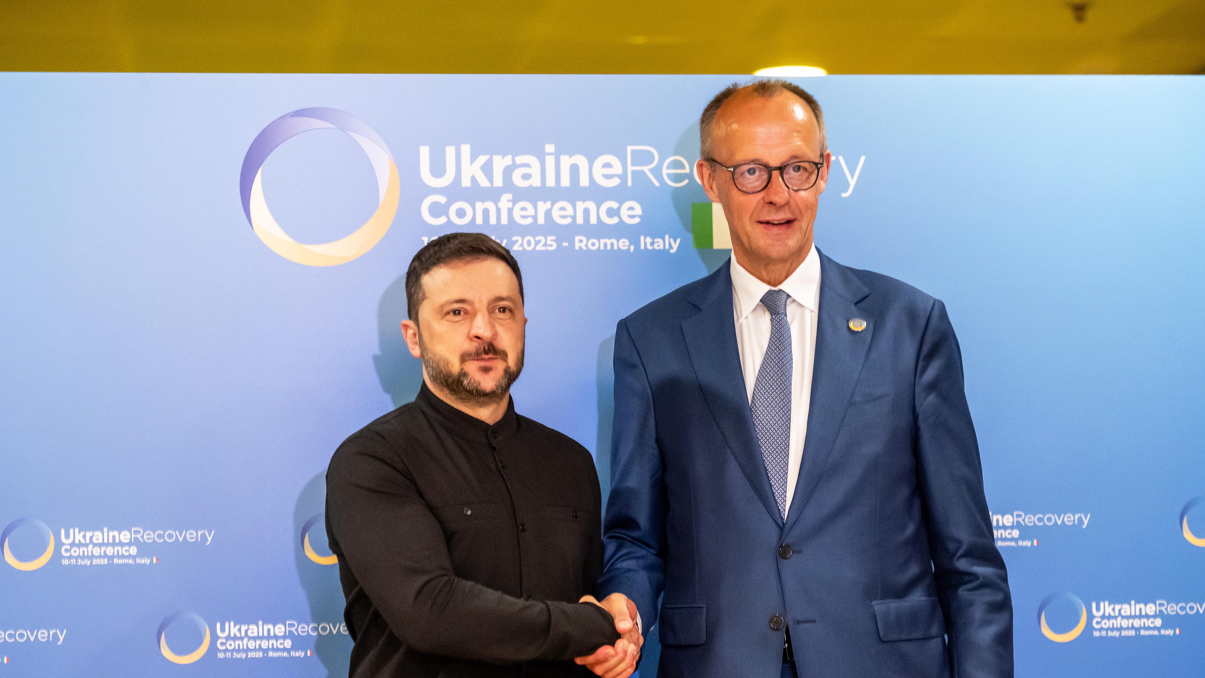 Bundeskanzler Friedrich Merz (CDU, r) und Wolodymyr Selenskyj, Präsident der Ukraine, geben sich vor einem bilateralen Gespräch bei der Wiederaufbaukonferenz für die Ukraine die Hand.