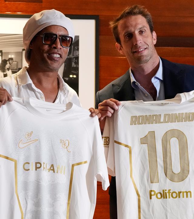 Ronaldinho hält das weiße trikot seines neuen Klubs hoch.
