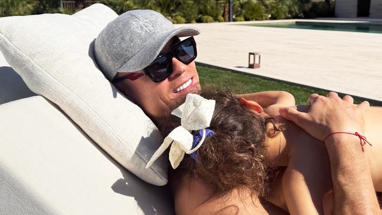 Fußballer Ronaldo liegt auf einer Sonnenliege mit seiner Tochter auf dem Bauch.