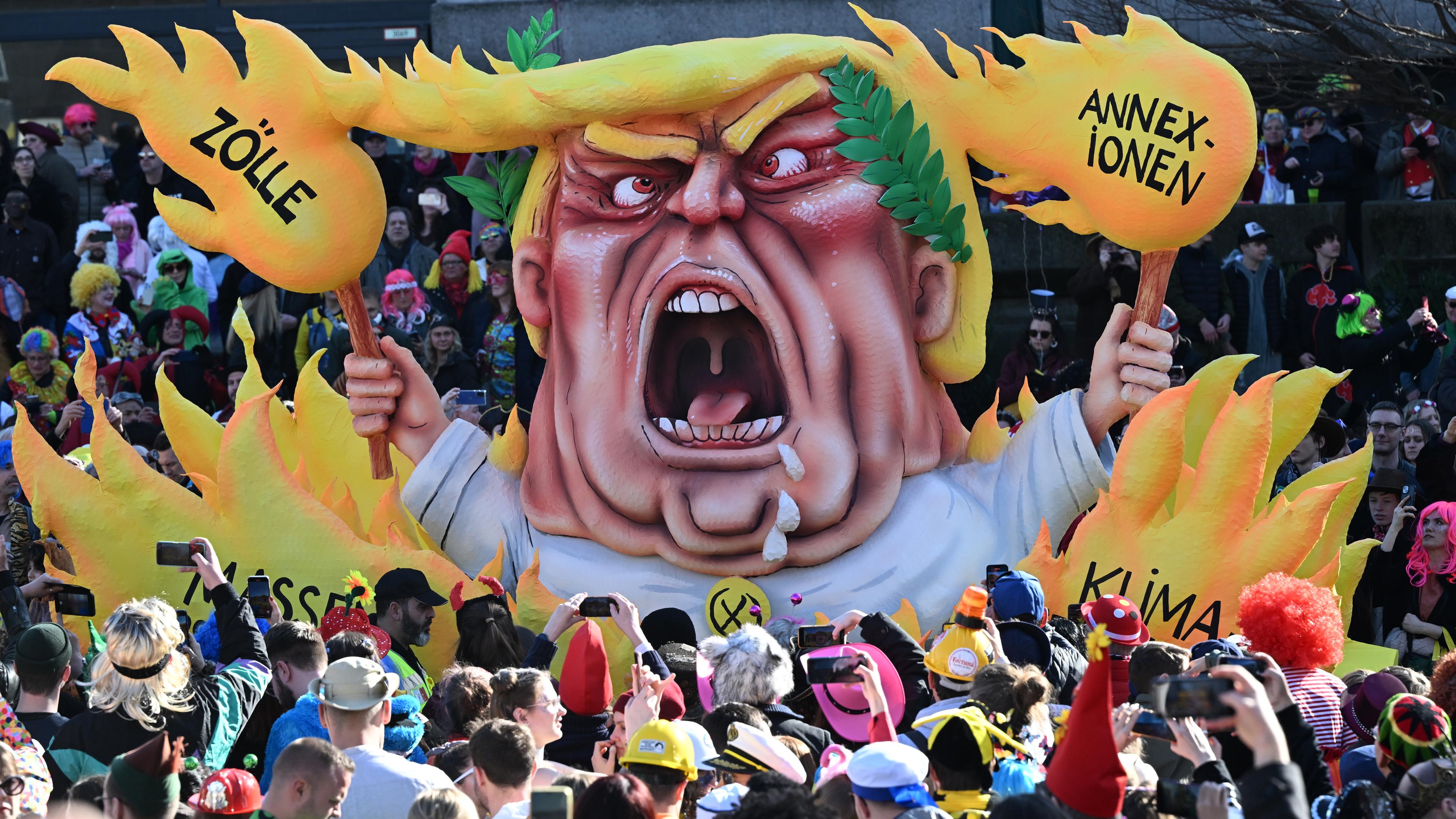 Nordrhein-Westfalen, Düsseldorf: Ein Mottowagen beim Rosenmontagszug zeigt Trump umgeben von Flammen, auf welchen die Worte stehen "Annexionen, Zölle, Klimazerstörung, Massenabschiebungen".