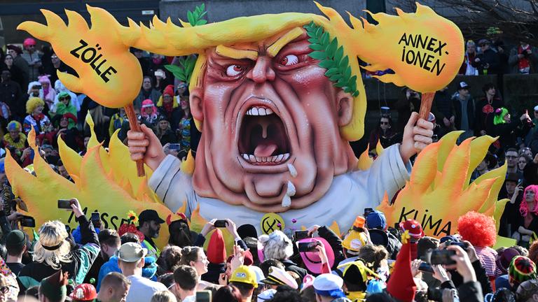Nordrhein-Westfalen, Düsseldorf: Ein Mottowagen beim Rosenmontagszug zeigt Trump umgeben von Flammen, auf welchen die Worte stehen "Annexionen, Zölle, Klimazerstörung, Massenabschiebungen".