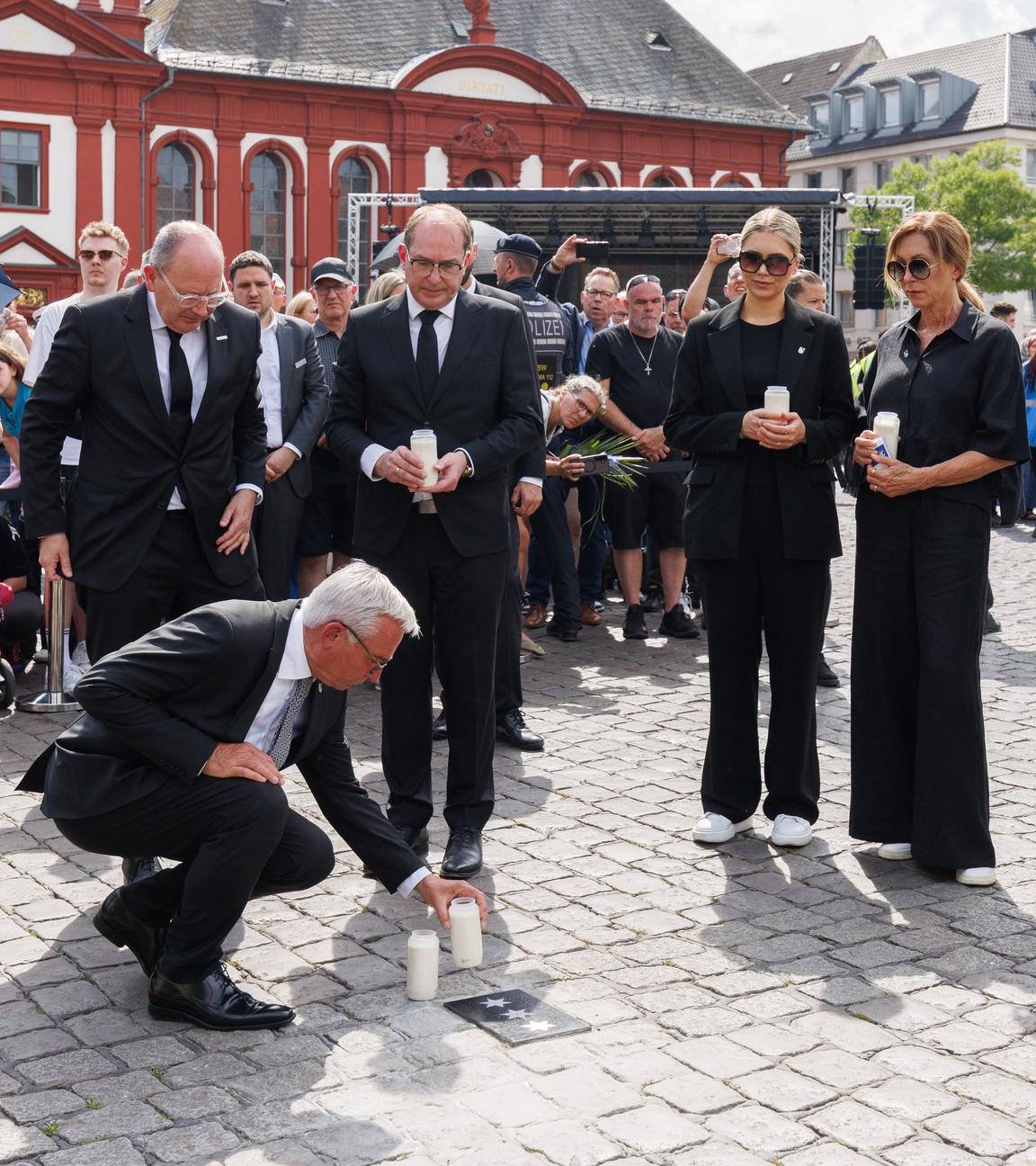 Thomas Strobl (CDU), Innenminister von Baden-Württemberg, stellt eine Kerze an einer Bodenplatte auf, die in Gedenken an Rouven Laur auf dem Marktplatz eingelassen wurde. Hinter Strobl stehen Christian Specht (CDU), Oberbürgermeister von Mannheim, Alexander Dobrindt (CSU), Bundesinnenminister, Angehörige von Laur, Polizeipräsidentin des Polizeipräsidiums Mannheim, Ulrike Schäfer, und Stefanie Hinz, Landespolizeipräsidentin von Baden-Württemberg.