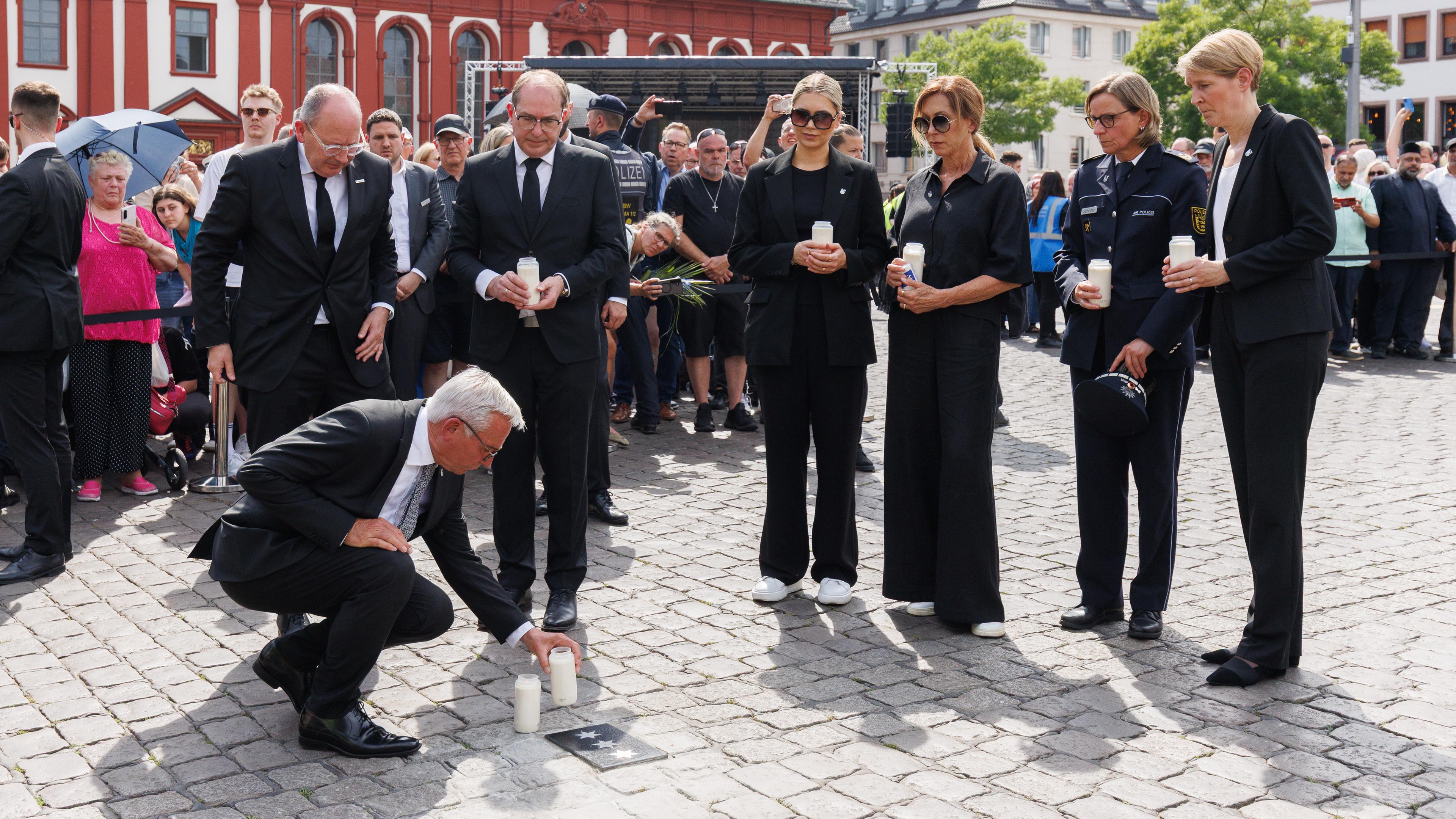 Thomas Strobl (CDU), Innenminister von Baden-Württemberg, stellt eine Kerze an einer Bodenplatte auf, die in Gedenken an Rouven Laur auf dem Marktplatz eingelassen wurde. Hinter Strobl stehen Christian Specht (CDU), Oberbürgermeister von Mannheim, Alexander Dobrindt (CSU), Bundesinnenminister, Angehörige von Laur, Polizeipräsidentin des Polizeipräsidiums Mannheim, Ulrike Schäfer, und Stefanie Hinz, Landespolizeipräsidentin von Baden-Württemberg.