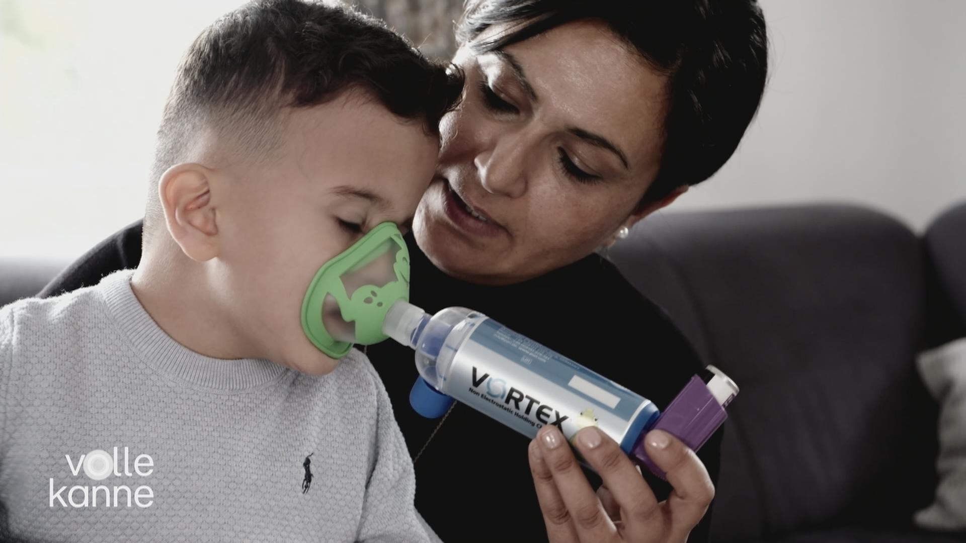 Mutter hält Kind mit Inhalator.
