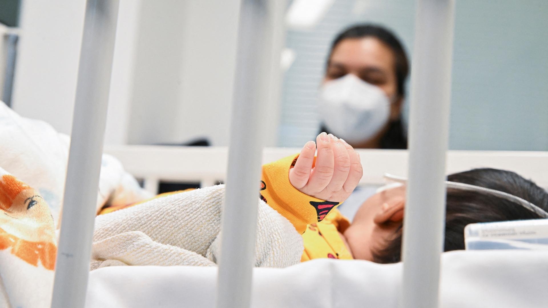 Eine Mutter beobachtet ihr Kind auf der Intensivstation, welches am RS-Virus erkrankt ist.