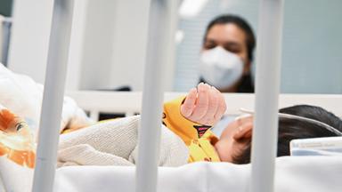 Eine Mutter beobachtet ihr Kind auf der Intensivstation, welches am RS-Virus erkrankt ist.