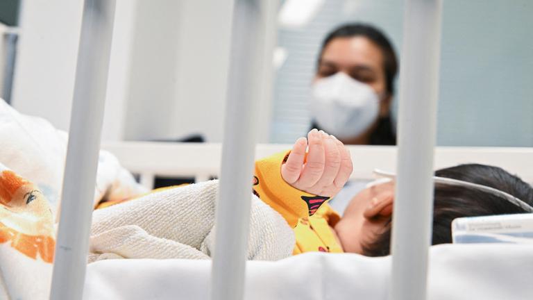 Eine Mutter beobachtet ihr Kind auf der Intensivstation, welches am RS-Virus erkrankt ist.