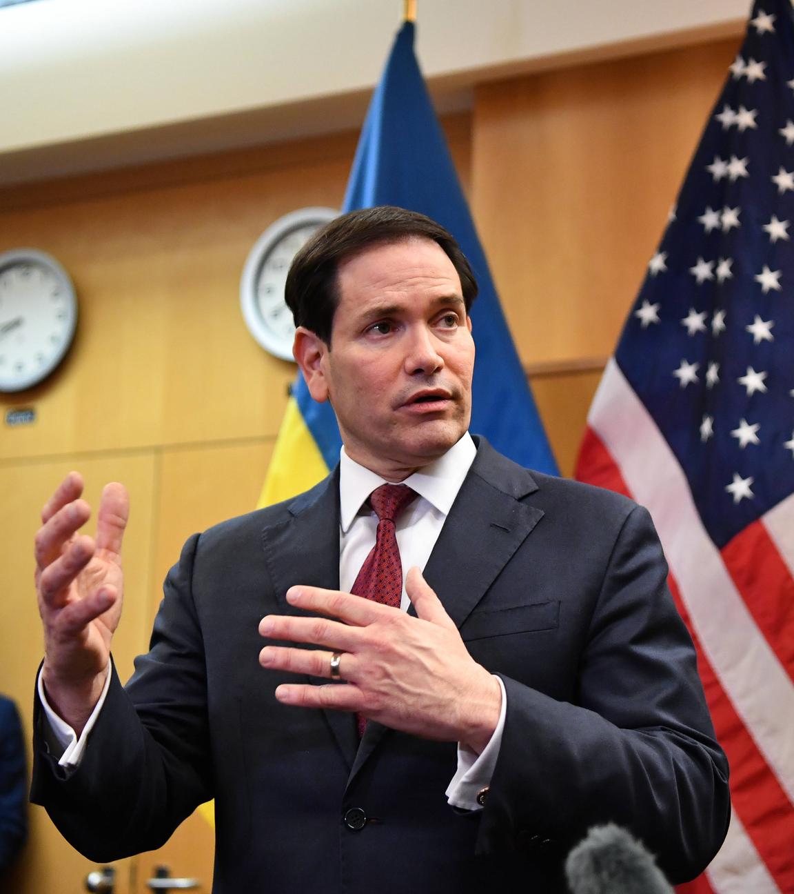 US-Außenminister Rubio nimmt an der Pressekonferenz in Genf bezüglich des Ukraine-Krieges teil. Er steht aufrecht und hinter ihm sind die Flaggen der USA und der Ukraine.