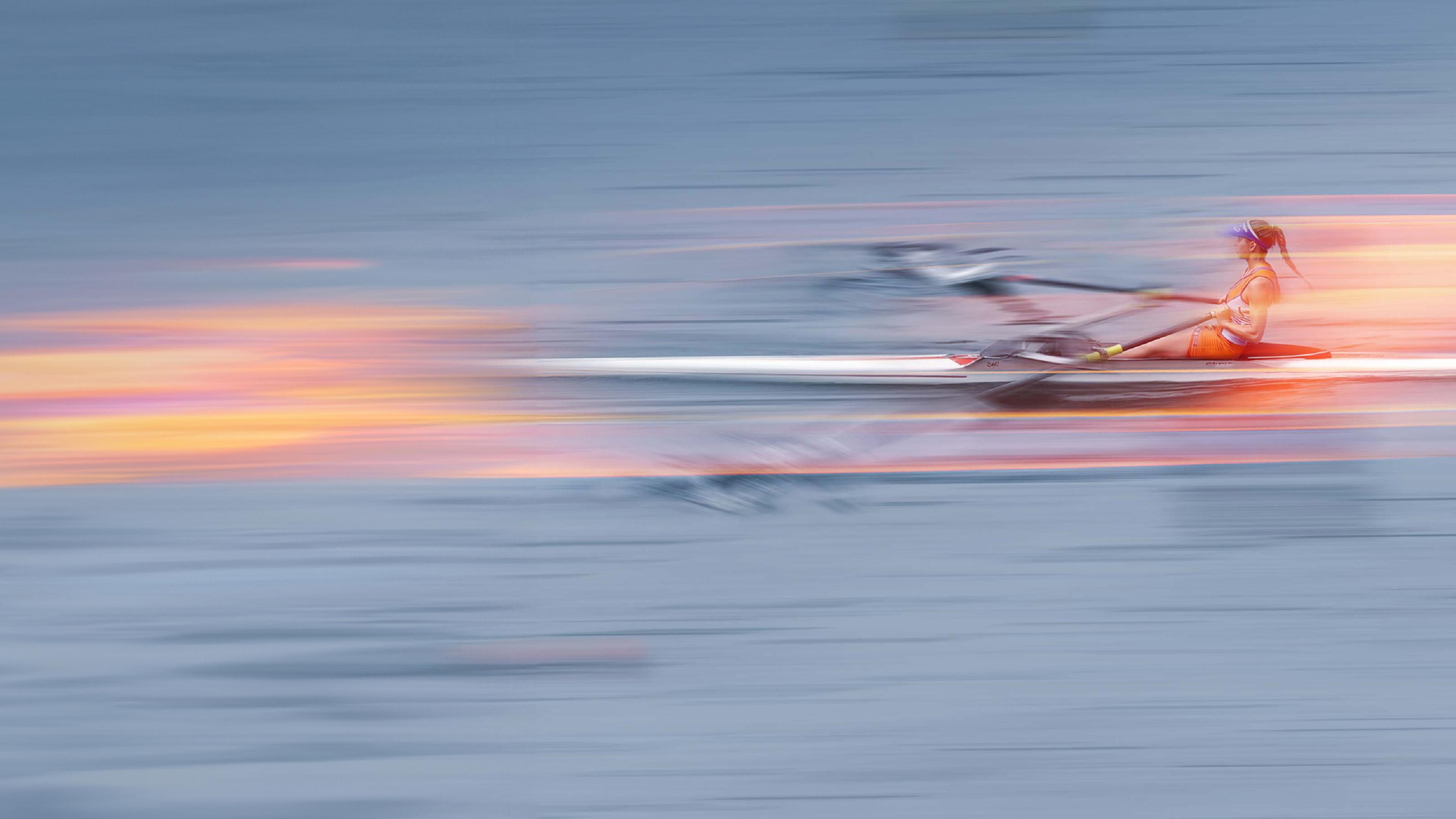 Eine Ruderin im Boot auf dem Wasser, stilistisch verfremdet um Schnelligkeit anzudeuten.