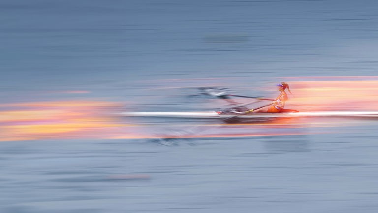 Eine Ruderin im Boot auf dem Wasser, stilistisch verfremdet um Schnelligkeit anzudeuten.