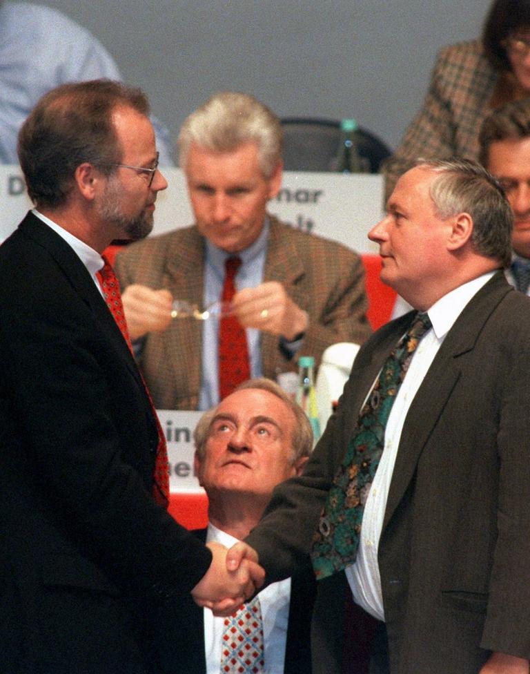 Mit einem Händedruck gratuliert Rudolf Scharping (l) seinem Nachfolger Oskar Lafontaine (r).