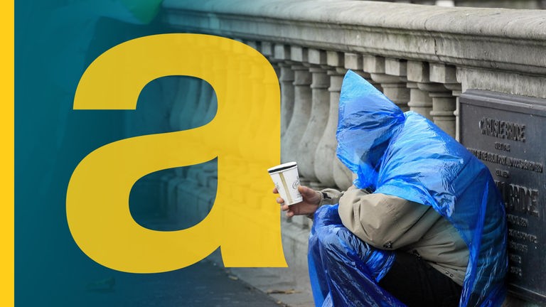 Ein Obdachloser sitzt mit einem Becher neben einer irischen Flagge