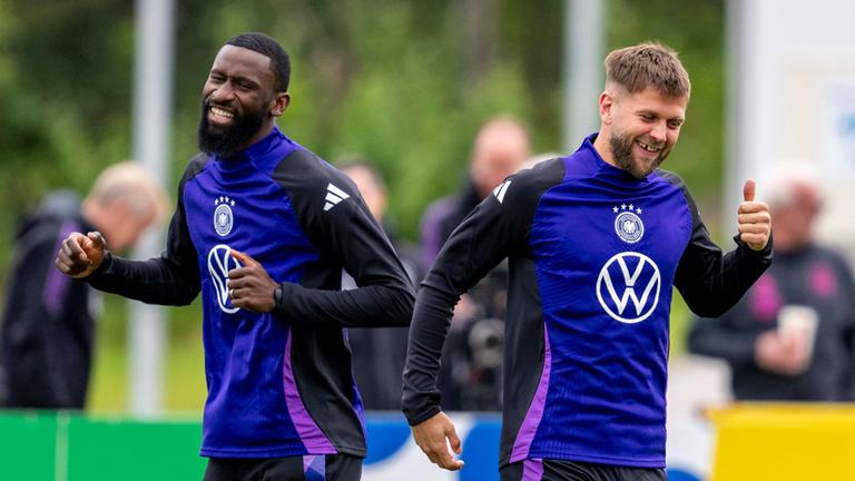 Antonio Rüdiger (l.) und Deutschlands Niclas Füllkrug lachen gemeinsam. 
