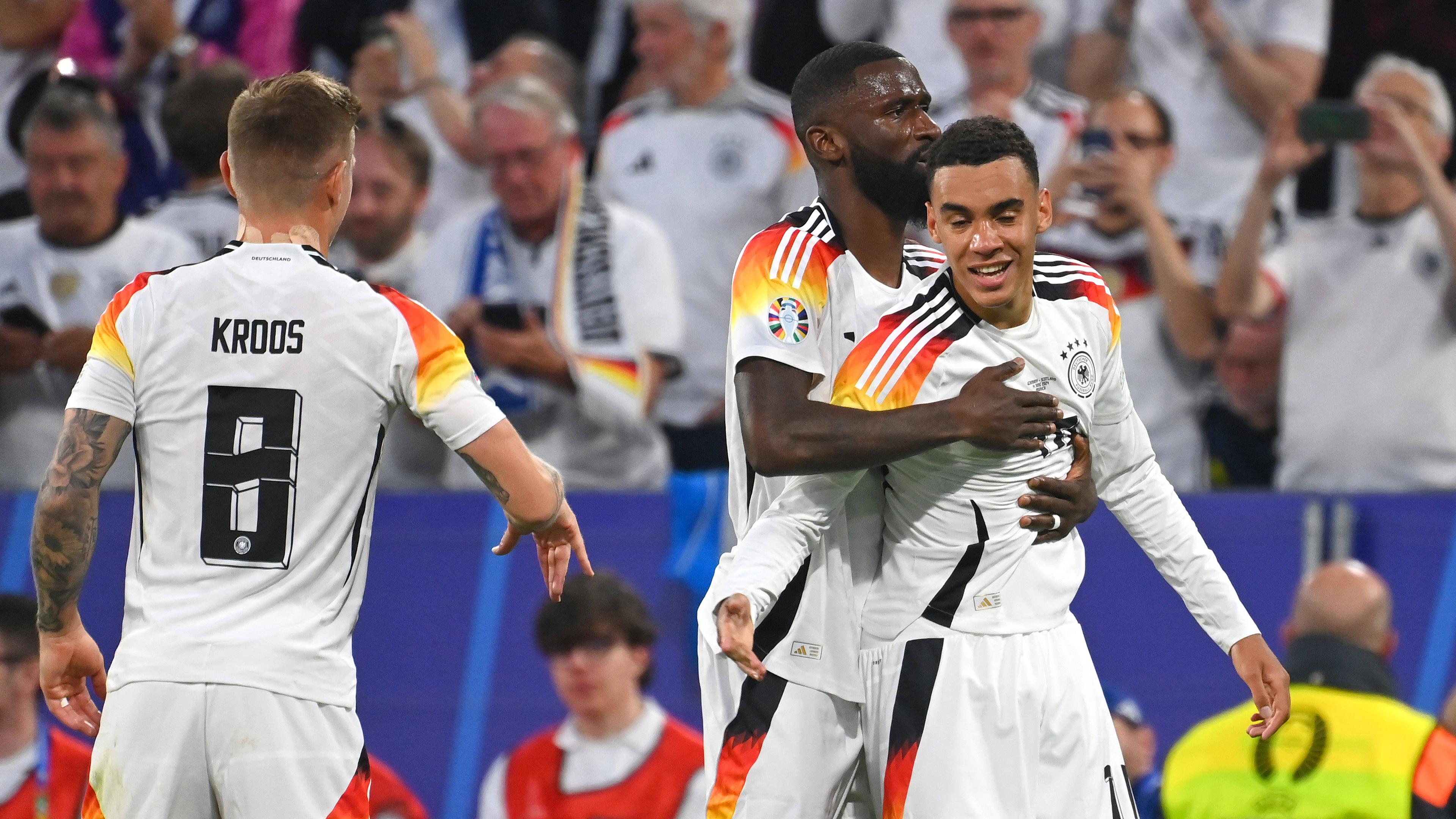 EM-Eröffnungsspiel Deutschland - Schottland am 14.6.2024 in München: Antonio Rüdiger gratuliert Jamal Musiala (rechts) zu seinem Tor. Links Toni Kroos.