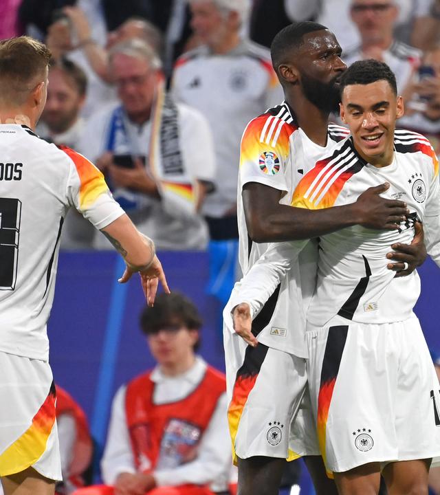 EM-Eröffnungsspiel Deutschland - Schottland am 14.6.2024 in München: Antonio Rüdiger gratuliert Jamal Musiala (rechts) zu seinem Tor. Links Toni Kroos.