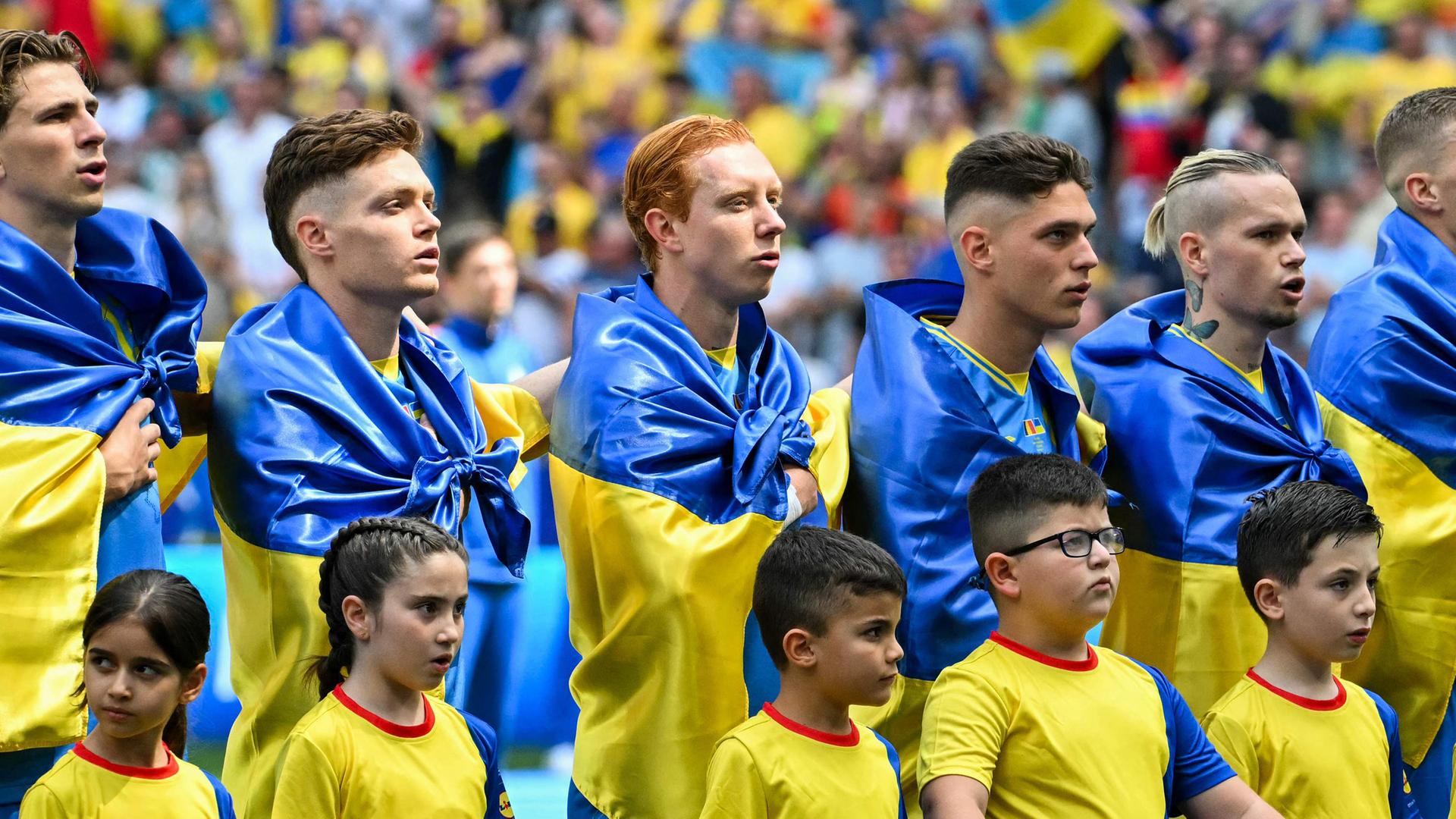 Die Spieler der Ukraine stellen sich vor dem Fußballspiel der UEFA Euro 2024 Gruppe E zwischen Rumänien und der Ukraine in der Münchner Fußballarena am 17. Juni 2024 auf