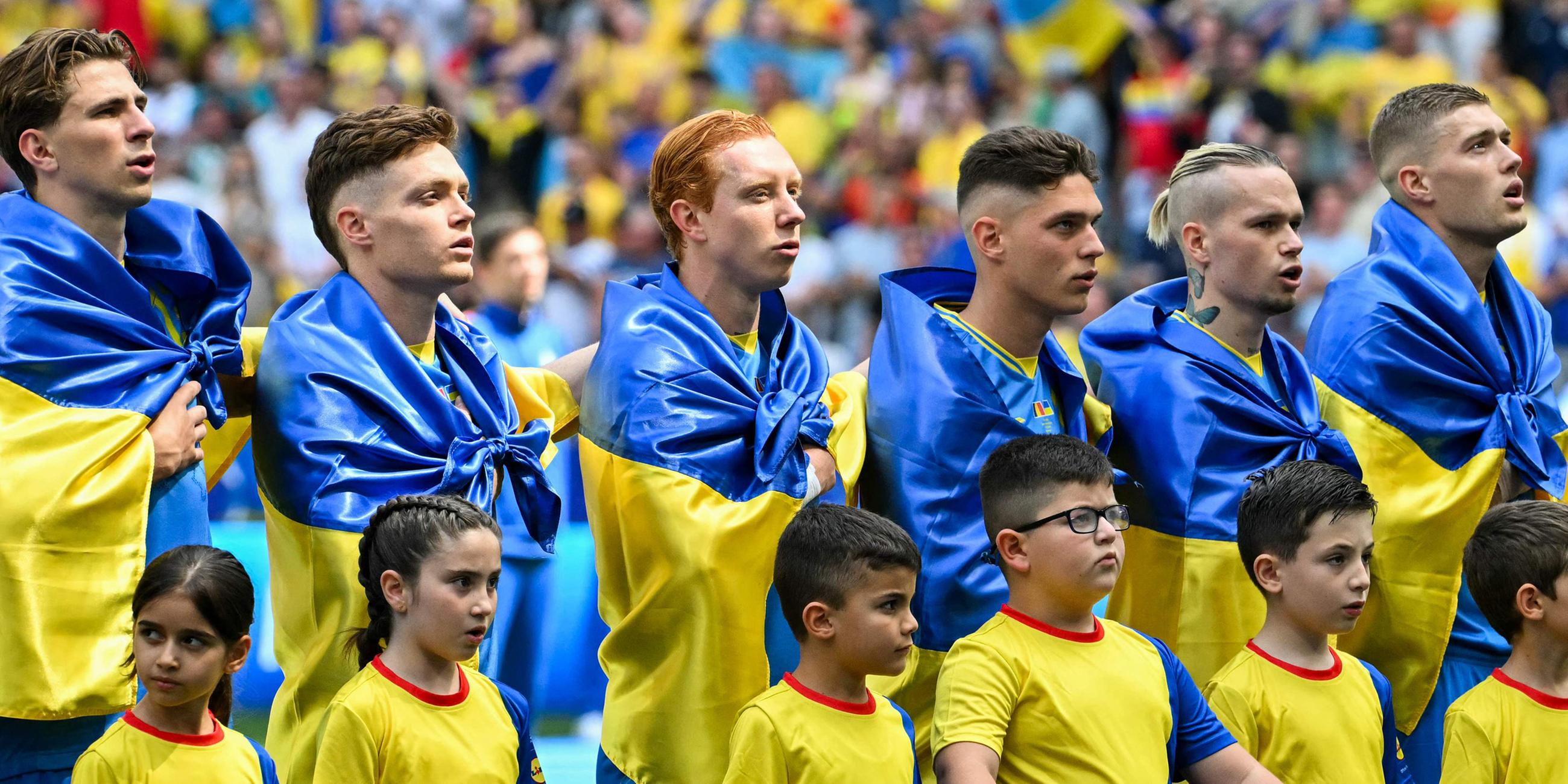 Die Spieler der Ukraine stellen sich vor dem Fußballspiel der UEFA Euro 2024 Gruppe E zwischen Rumänien und der Ukraine in der Münchner Fußballarena am 17. Juni 2024 auf