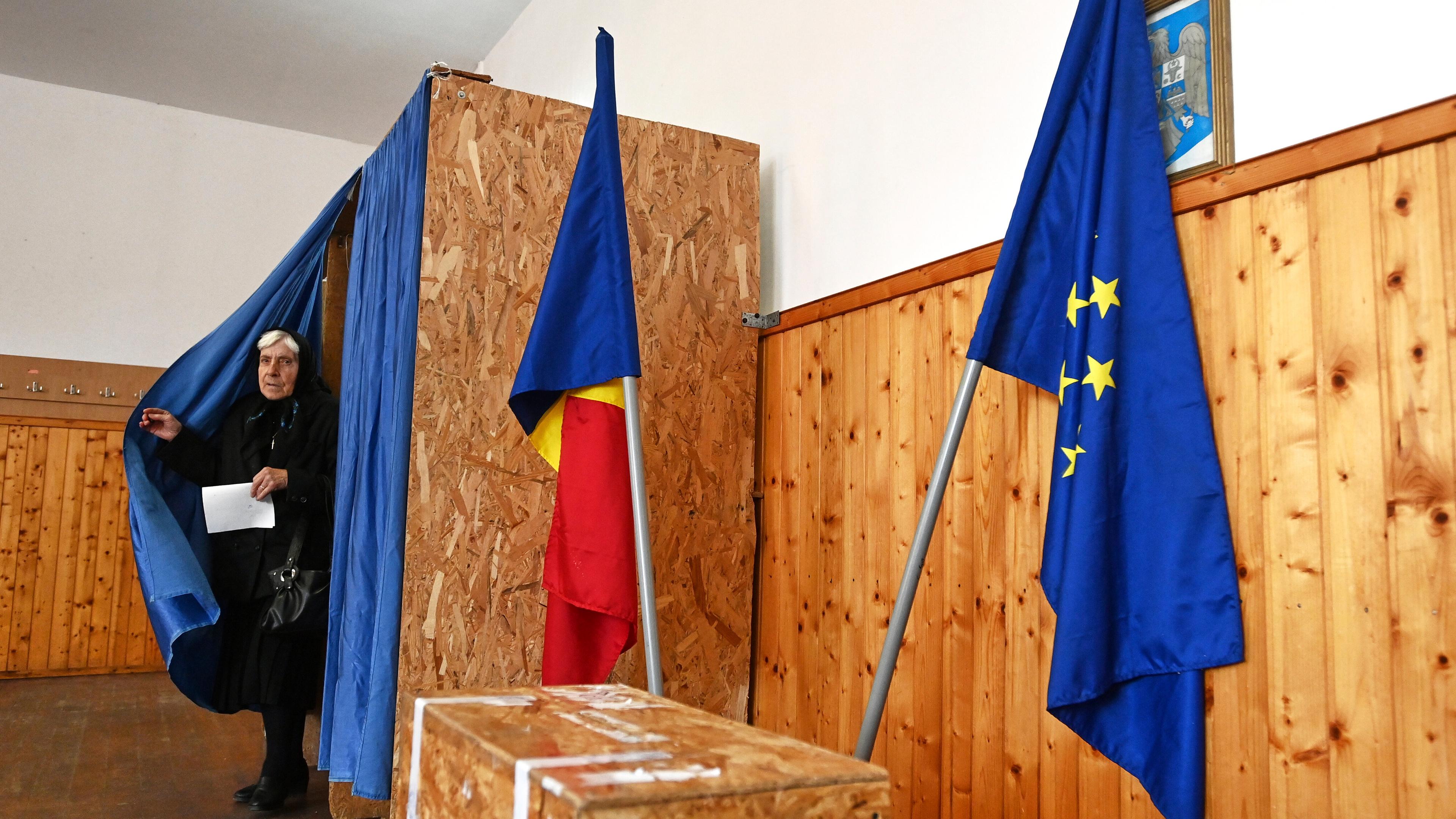 A woman exits a voting cabin before casting her ballot in the second round of the country's presidential election redo in Persani, Romania, Sunday, May 18, 2025. (AP Photo/Eduard Vinatoru)