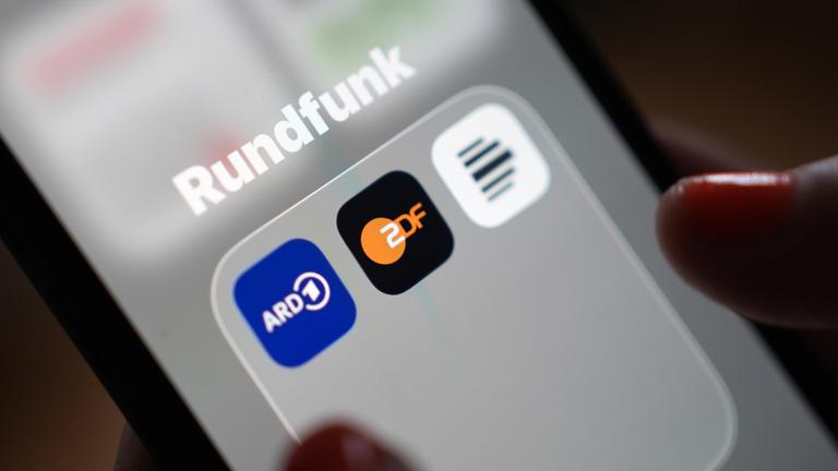 Auf dem Bildschirm eines Smartphones sind die App-Icons von ARD, ZDF und Deutschlandfunk im Ordner "Rundfunk" zu sehen.