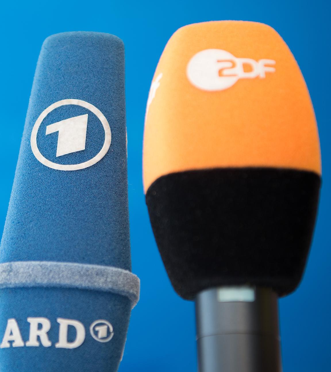 Die Mikrofone von ARD und ZDF sind vor einer Pressekonferenz nebeneinander aufgestellt.
