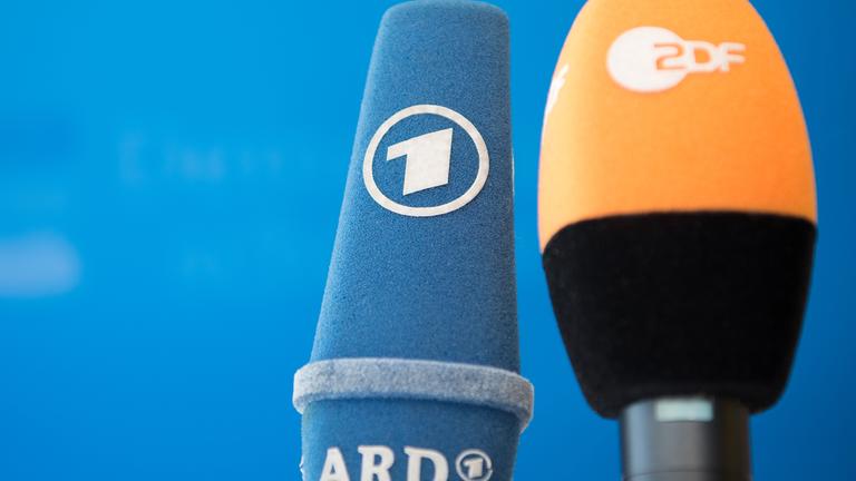 Die Mikrofone von ARD und ZDF sind vor einer Pressekonferenz nebeneinander aufgestellt.