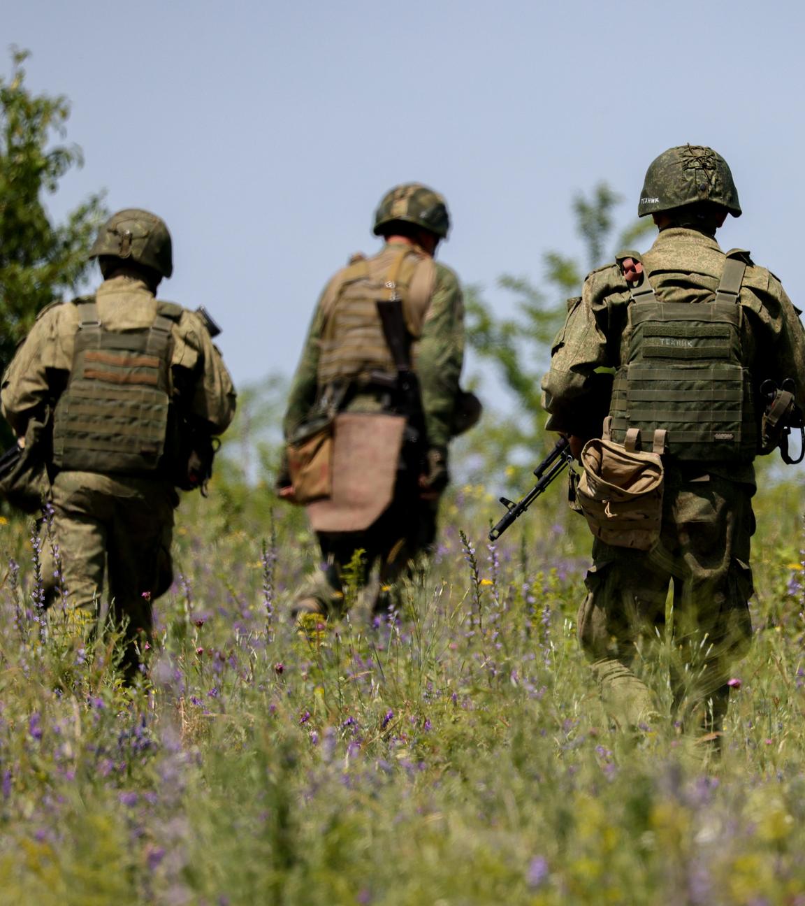 Vier Soldaten laufen durch eine Wiese.