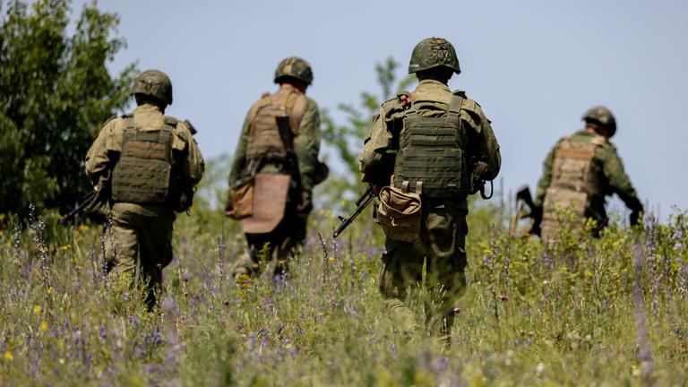Vier Soldaten laufen durch eine Wiese.