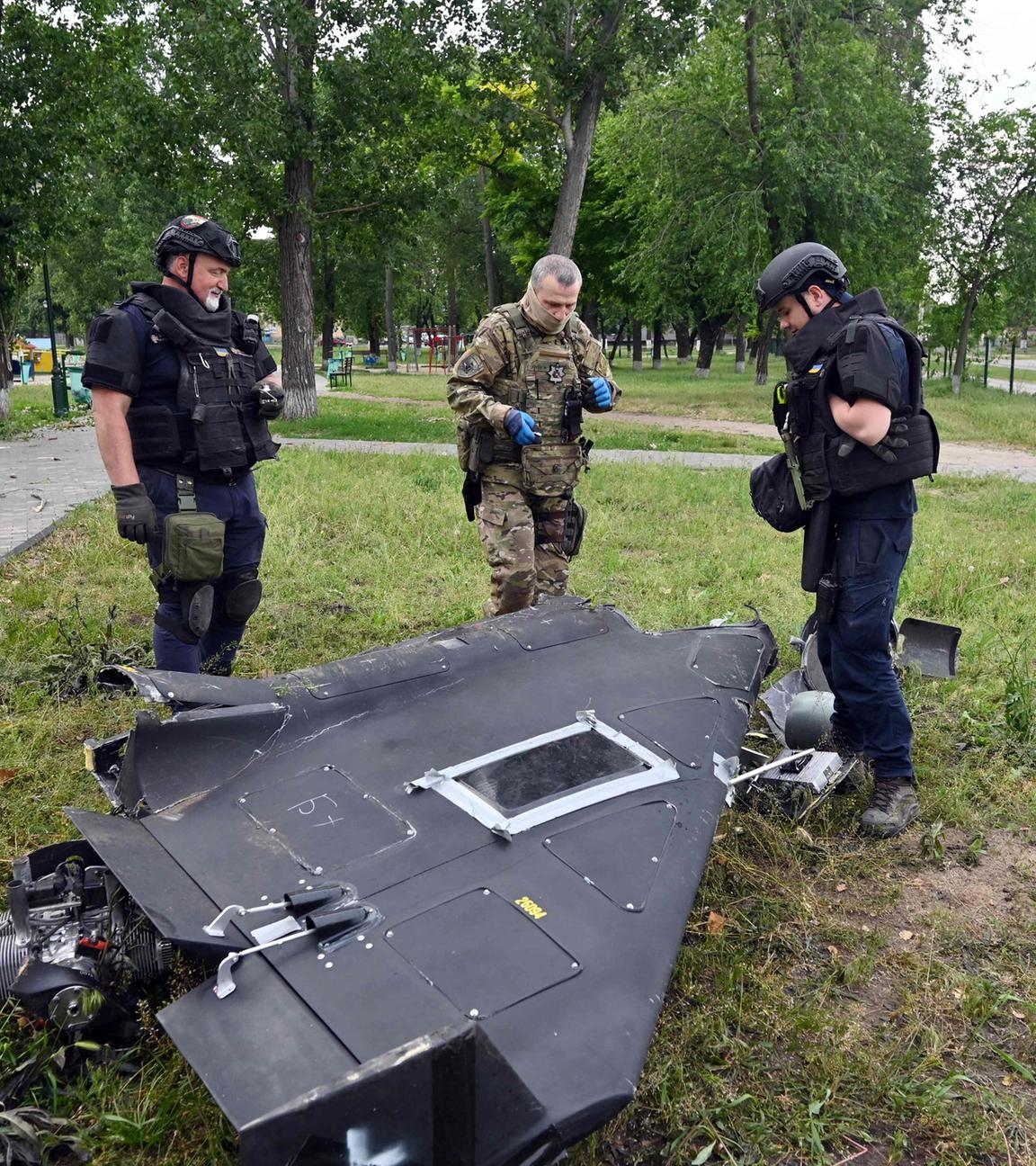 Ukrainische Sprengstoffexperten und Polizisten untersuchen Teile einer Militärdrohne vom Typ Shahed 136 nach einem Luftangriff in Charkiw.