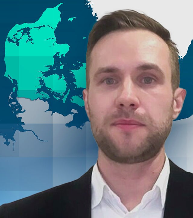Julian Pawlak, Experte für maritime Sicherheit bei der Stiftung für Wissenschaft und Politikin einem schwarzen Sakko und weißem Hemd. Im hintergrund ist eine weiße Wand.