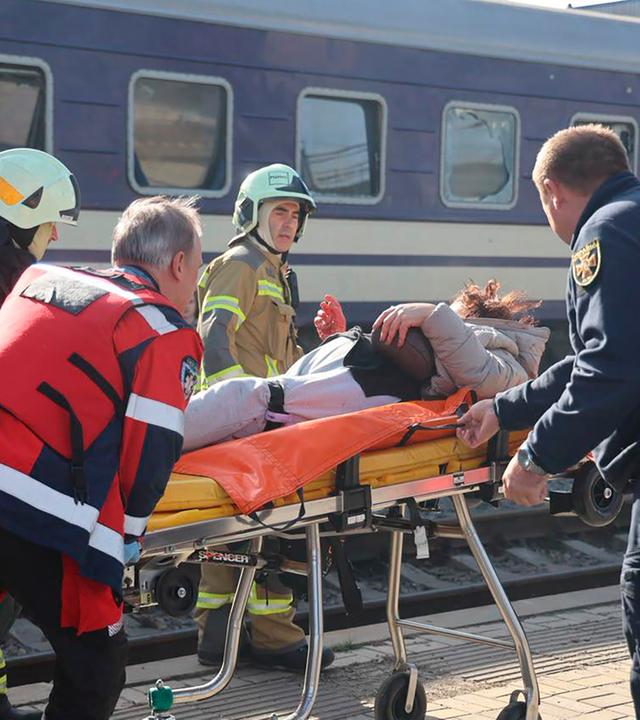 Rettungskräfte evakuieren einen verletzten Zivilisten nach einem russischen Drohnenangriff auf einem Bahnsteig