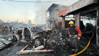 Ein Feuerwehrman läuft an ausgebrannten Autos und zerstörten Gebäuden vorbei.