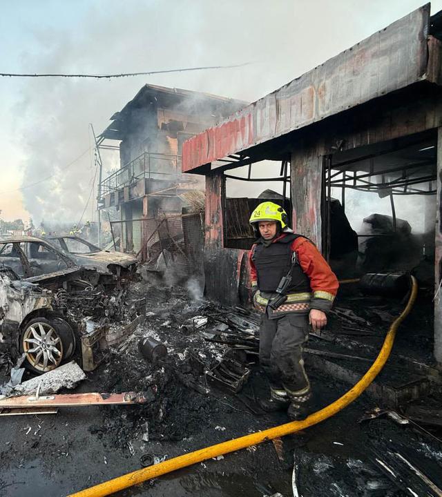 Ein Feuerwehrman läuft an ausgebrannten Autos und zerstörten Gebäuden vorbei.