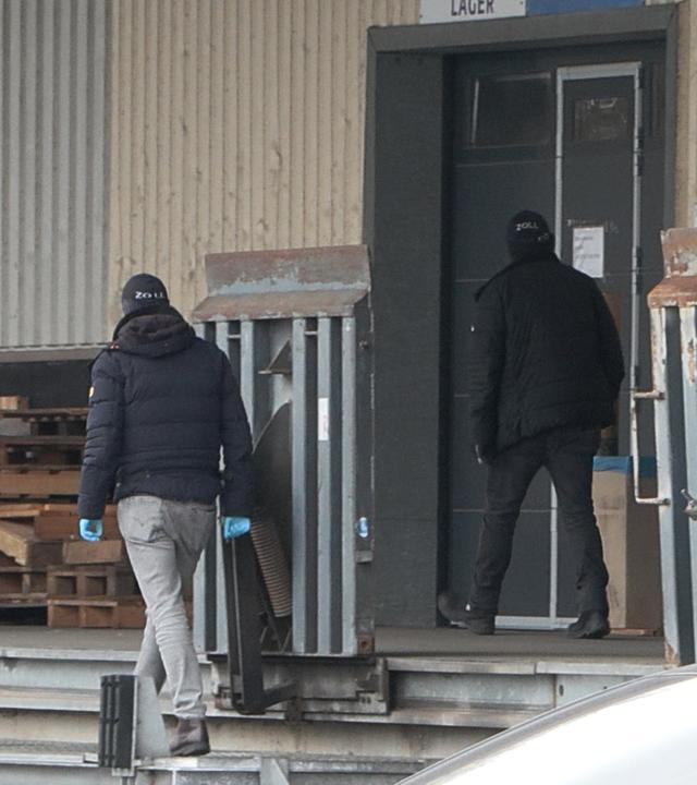 Mehrere Beamte untersuchen eine Lagerhalle