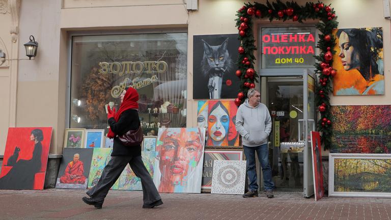 Eine Frau geht an einem Wintertag in Moskau, Russland, auf einer Straße vor einem Souvenirladen entlang.