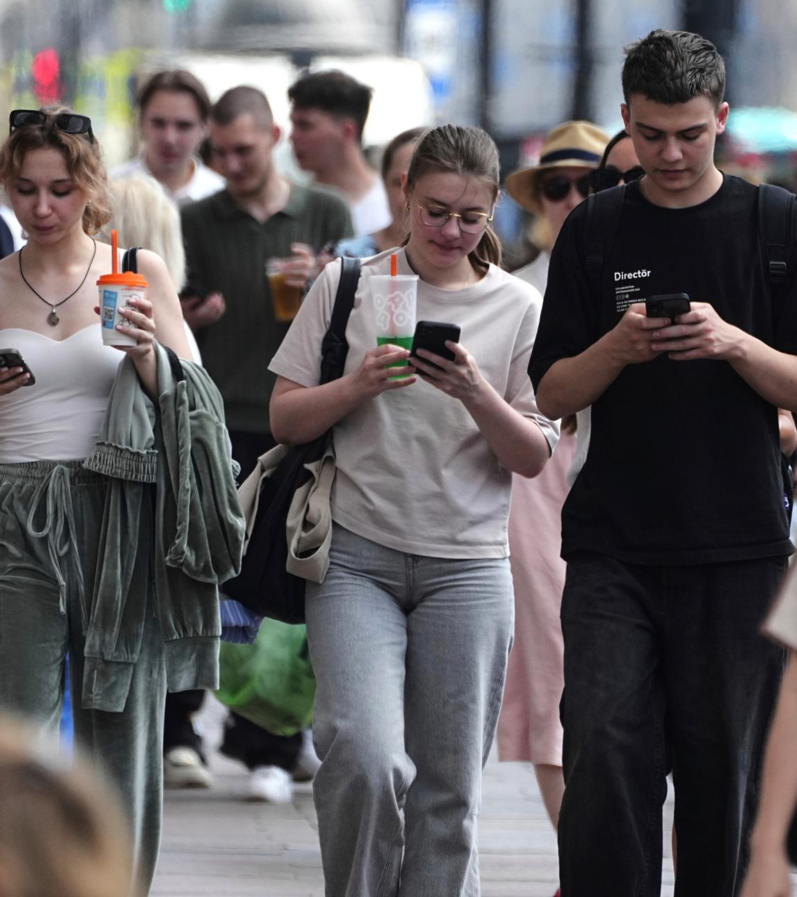 Fußgänger schauen auf ihre Handys, während sie durch St. Petersburg, Russland, gehen, Archivbild