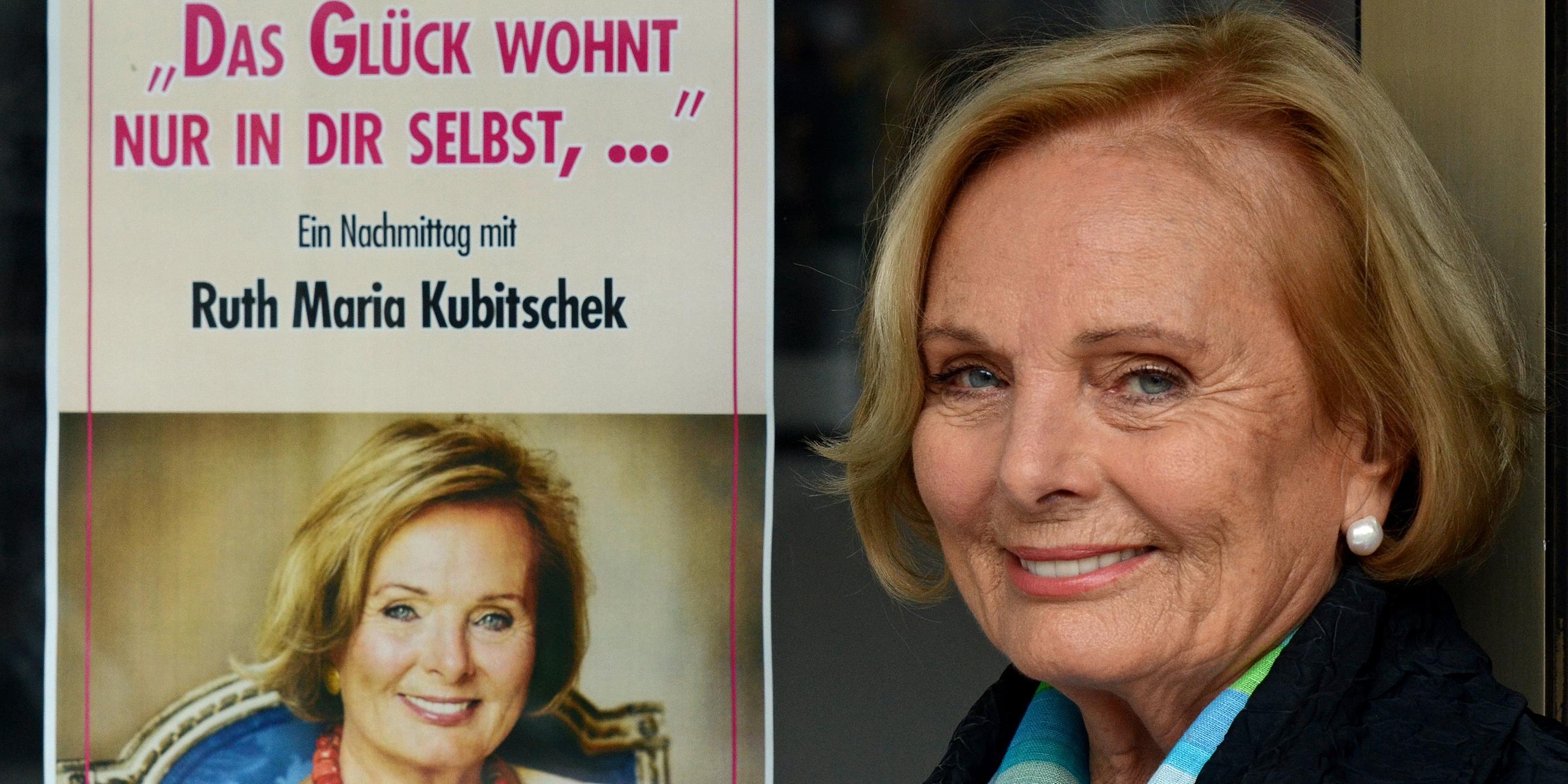 Die Schauspielerin Ruth Maria Kubitschek posiert neben einem Plakat zu ihrer Lesung "Das Glück wohnt nur in dir selbst,... Ein Nachmittag mit Ruth Maria Kubitschek". 
